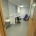 A room with a door, blue chair, black chair, sink and desk